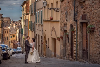 Wedding couple standing in the street  in Volterra, Italy during pre-wedding photo shoot