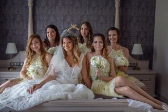 Bride and bridesmaids sitting on a bed