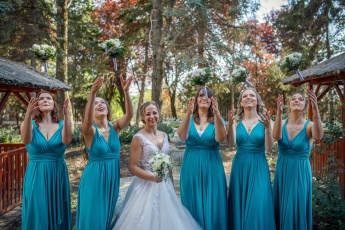 Braut und Brautjungfern werfen Blumensträuße in die Luft